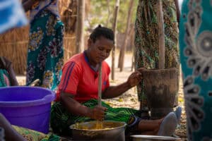 Malawian woman cooking traditional food outdoors in a rural setting.