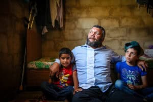 Refugee father with two children in a modest home.