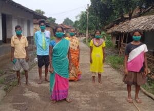 six people wearing face masks and social distancing in rural street
