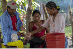 three people sort food items into bowls in Honduras