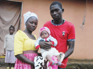 A couple holding their newborn baby outdoors in a rural Nigerian community