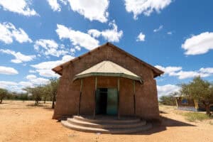 Rural church with simple structure and steps, under a blue sky with clouds.