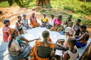 A community savings group sitting outside in a circle.