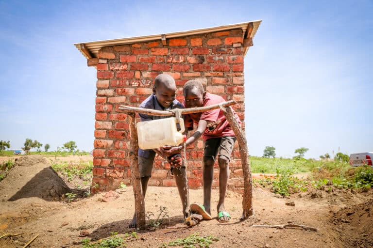 Community members washing their hands at a locally made tippy tap handwashing station.