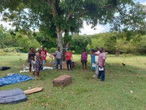 Haitian community gathering under a large tree for support and hope.