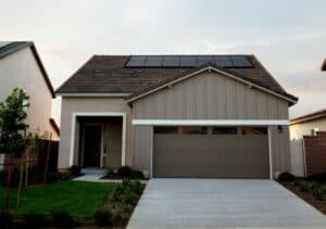 A single-family home with rooftop solar panels, a driveway, and a garage, photographed in daylight.