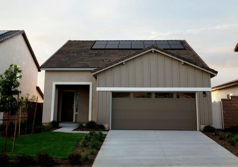 A single-family home with rooftop solar panels, a driveway, and a garage, photographed in daylight.