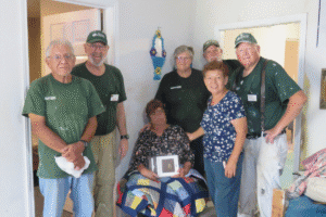 Several Disaster Response Services volunteers stand with a seated homeowner inside a repaired room of a house in Texas.