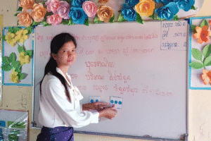 Teacher teaching in classroom with whiteboard and colorful decorations.