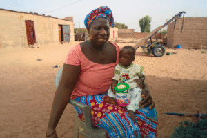 Woman and child in rural village with water pump in background.