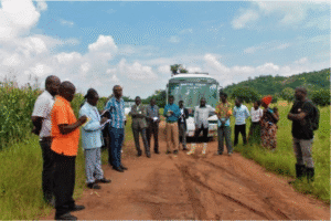 Community gathering with a bus in a rural setting for outreach programs.