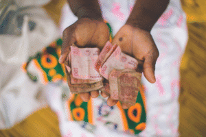 Hands holding Kenyan shillings, symbolizing aid and financial support.