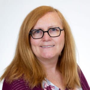 Portrait of Iona Stewart-Buisman with red hair and glasses.