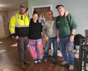 Group of four volunteers smiling indoors, showing teamwork and community support.