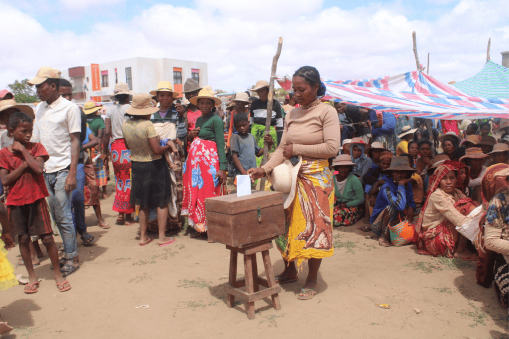 People gather around a woman making a donation at a community event in Madagascar.
