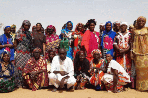 Group of African men and women in traditional attire outdoors.