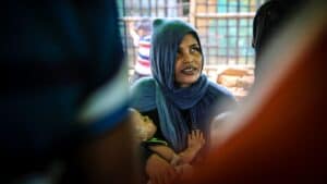 Community health counsellor holding a child during a maternal health discussion in Teknaf, Bangladesh.