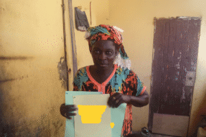 Woman holding a document in a modest room, representing aid and support.