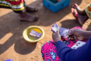 Person distributing cash aid to community members in a humanitarian setting.