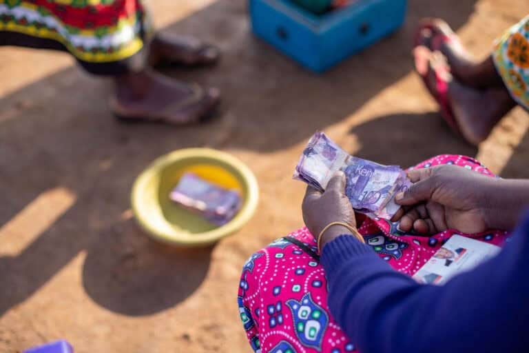 Person distributing cash aid to community members in a humanitarian setting.