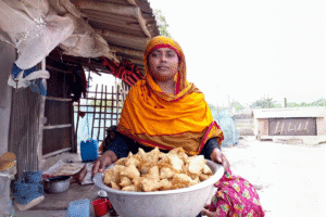 Woman selling fried snacks in a rural market in Bangladesh.
