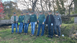 Group of volunteers cleaning up after storm damage in a wooded area.