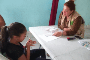 Woman and girl engaging in a community support discussion at a table.