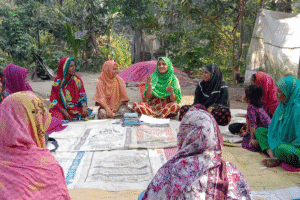 Women and children gather outdoors for community discussion and planning.