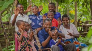 Group of Tanzanian children and adults smiling outdoors.