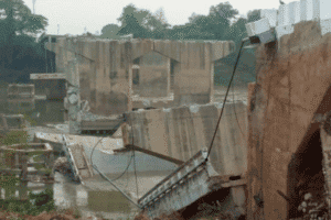 Collapsed bridge and damaged structures in a flood-affected area.