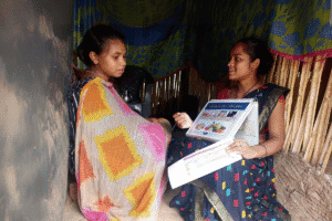 Women discussing aid programs inside a makeshift shelter.