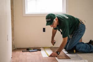 Volunteer installing flooring for community renovation project.