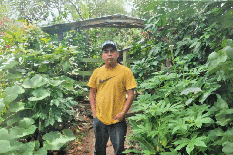 Young man in a yellow Nike t-shirt standing in lush garden.