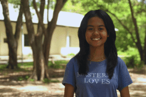 Smiling girl outdoors with trees in background for World Renew.