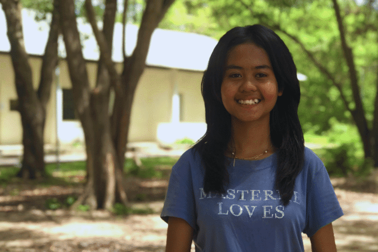 Smiling girl outdoors with trees in background for World Renew.