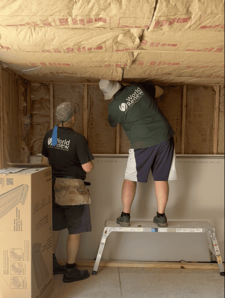 Volunteers working together to repair a wall in a disaster relief effort.