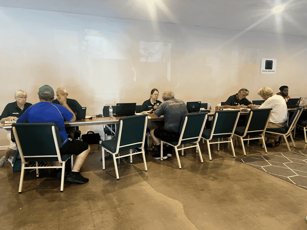 People gathered around a conference table discussing hurricane recovery efforts.