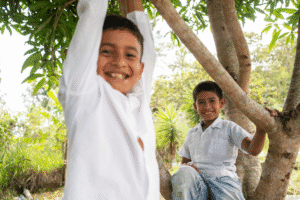 Smiling children enjoying outdoor play under a tree.