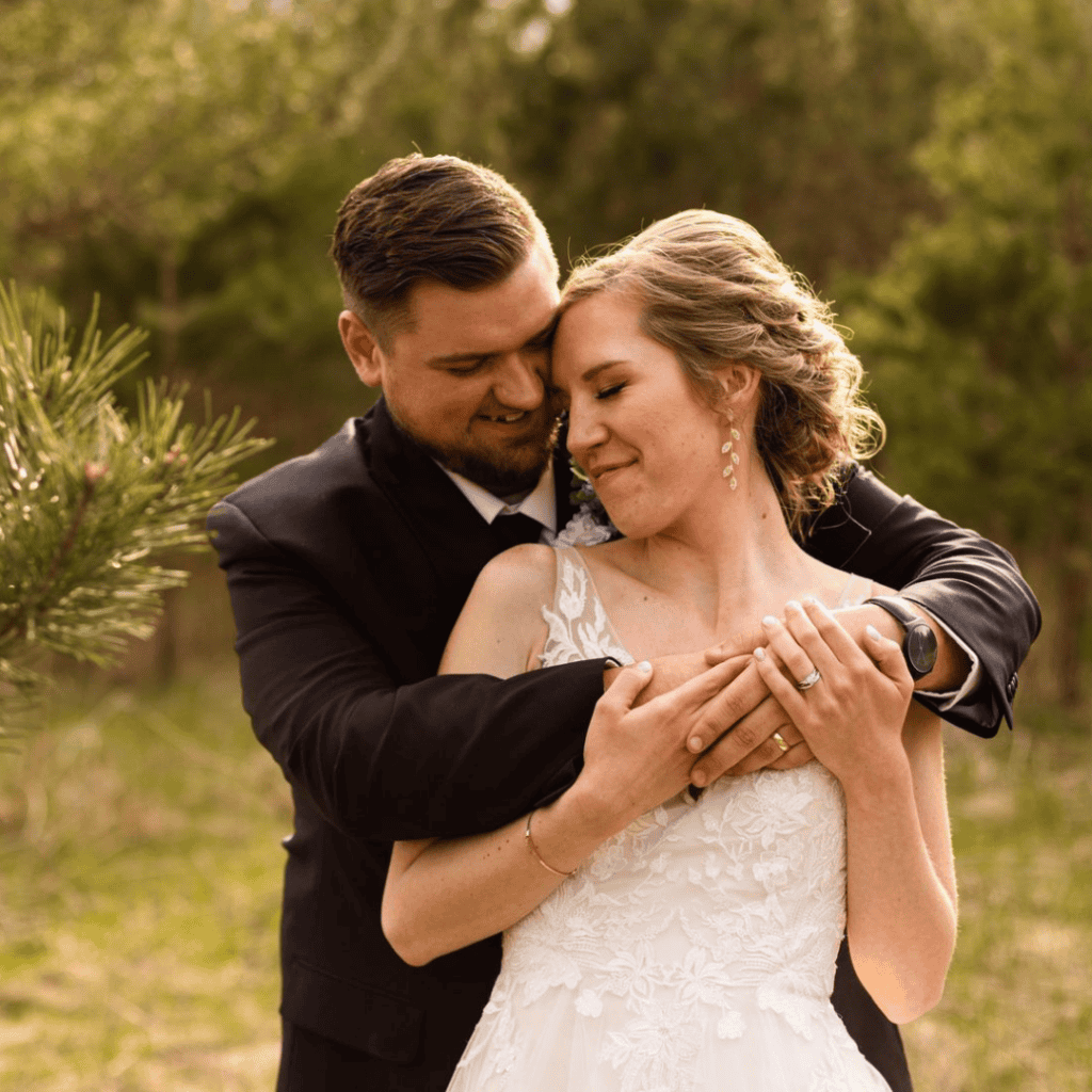 Happy wedding couple embracing in a natural outdoor setting.