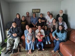 Large group of adults and children gathered together in a living room for a group photo.