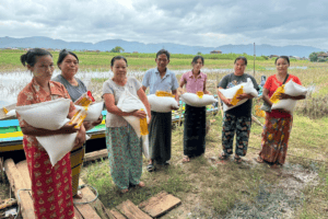 Women receiving aid supplies in a rural field for community support.