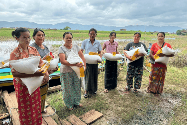 Women receiving aid supplies in a rural field for community support.