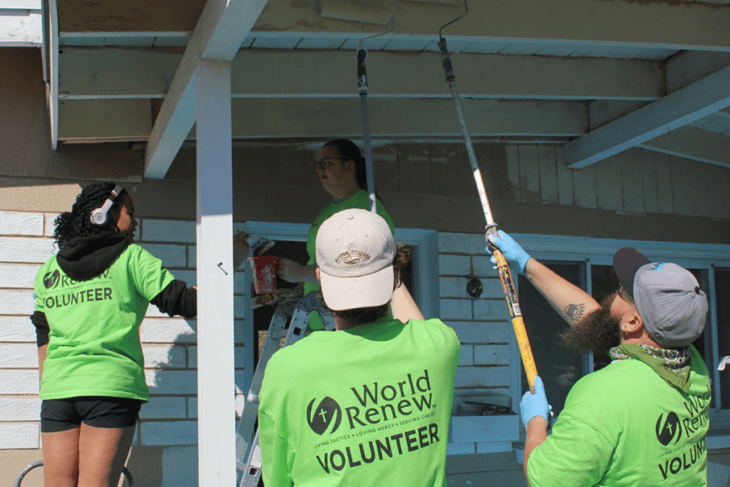 Volunteers painting a house for community development by World Renew.