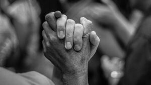 Close-up of two people holding hands in support and solidarity.