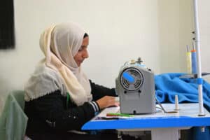 Woman sewing with a sewing machine in a community center.