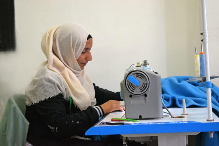 Woman sewing with a sewing machine in a community center.