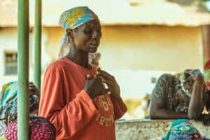 Woman praying in a community gathering for aid and support.