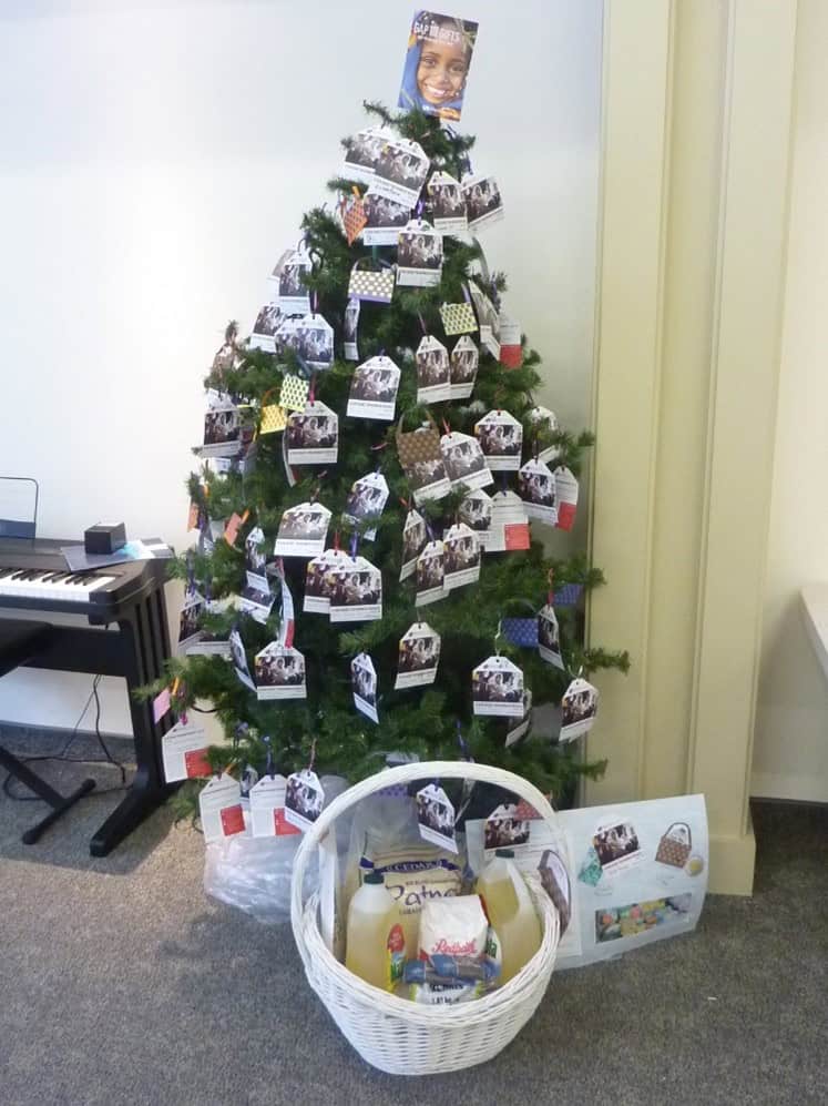 Christmas tree decorated with photos and gift tags for charity.