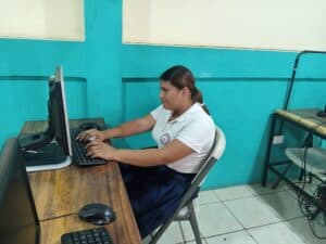 Young girl working on a desktop computer in a classroom setting.
