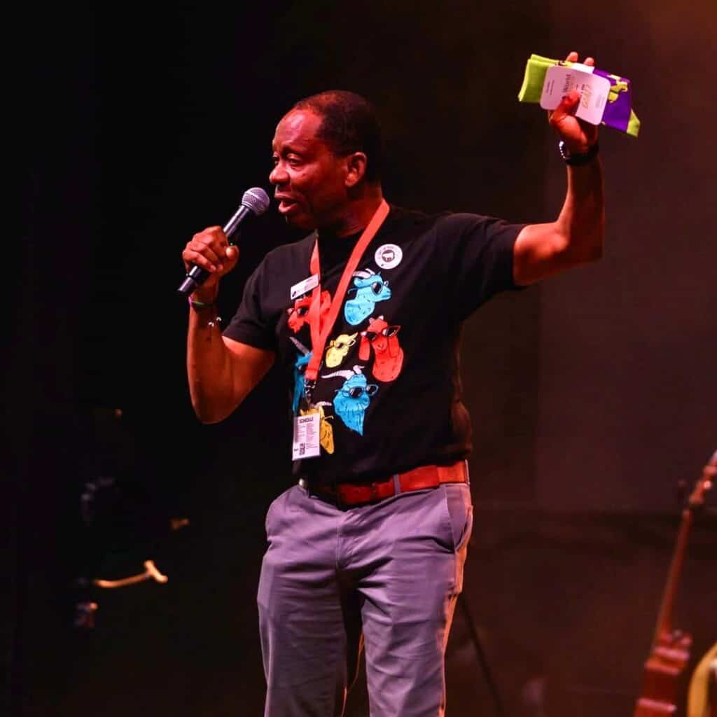 Youth speaker at AOYC 2026 event, engaging audience with microphone and colorful materials.